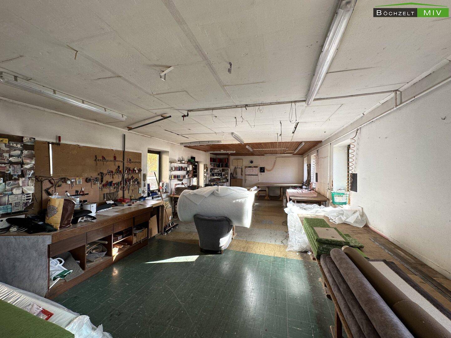 Großer Arbeitsraum oder Werkstatt mit Holzboden und vielen Materialien für handwerkliche Tätigkeiten.