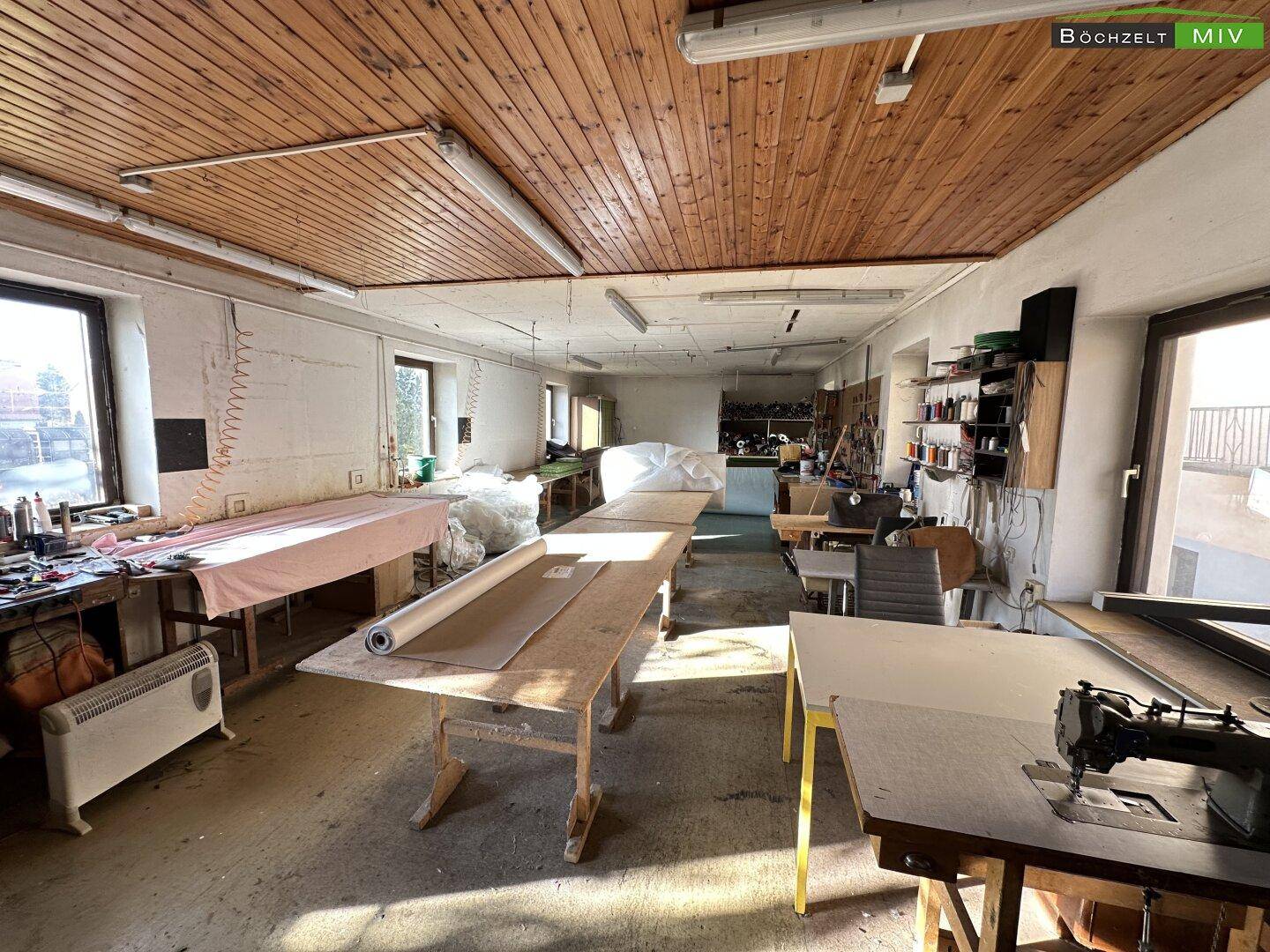 Werkstatt mit Holzboden, großen Fenstern und Arbeitsflächen für verschiedene Projekte.