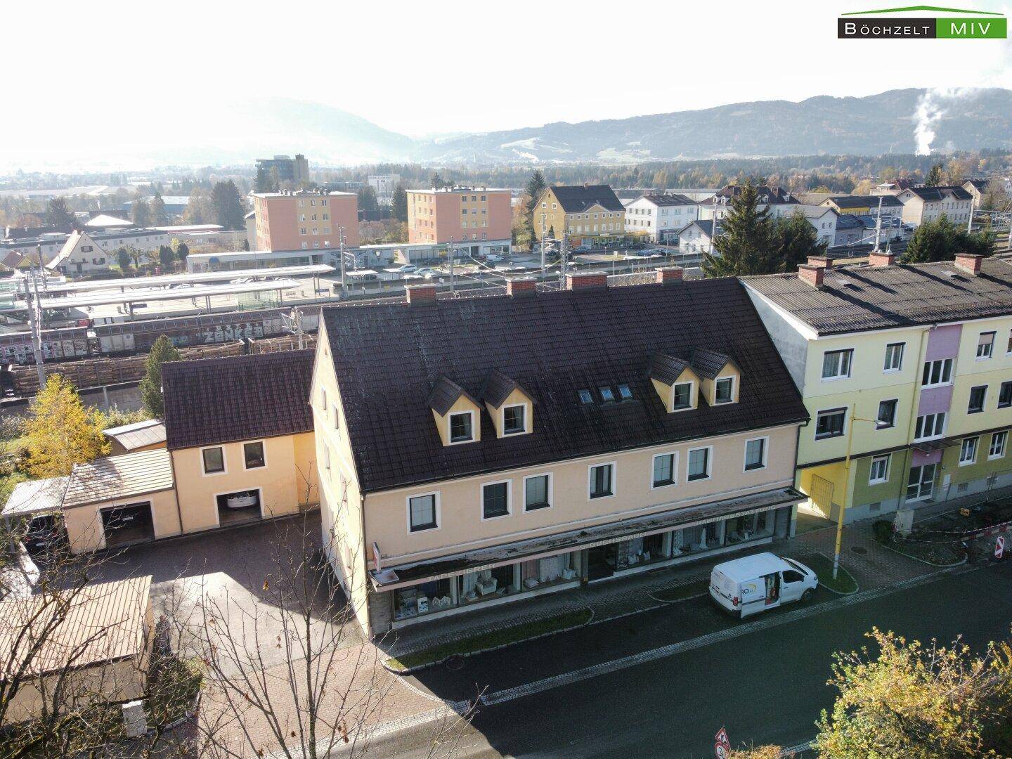 Luftaufnahme des Anwesens mit angrenzenden Bahngleisen und einer Bergkulisse im Hintergrund.