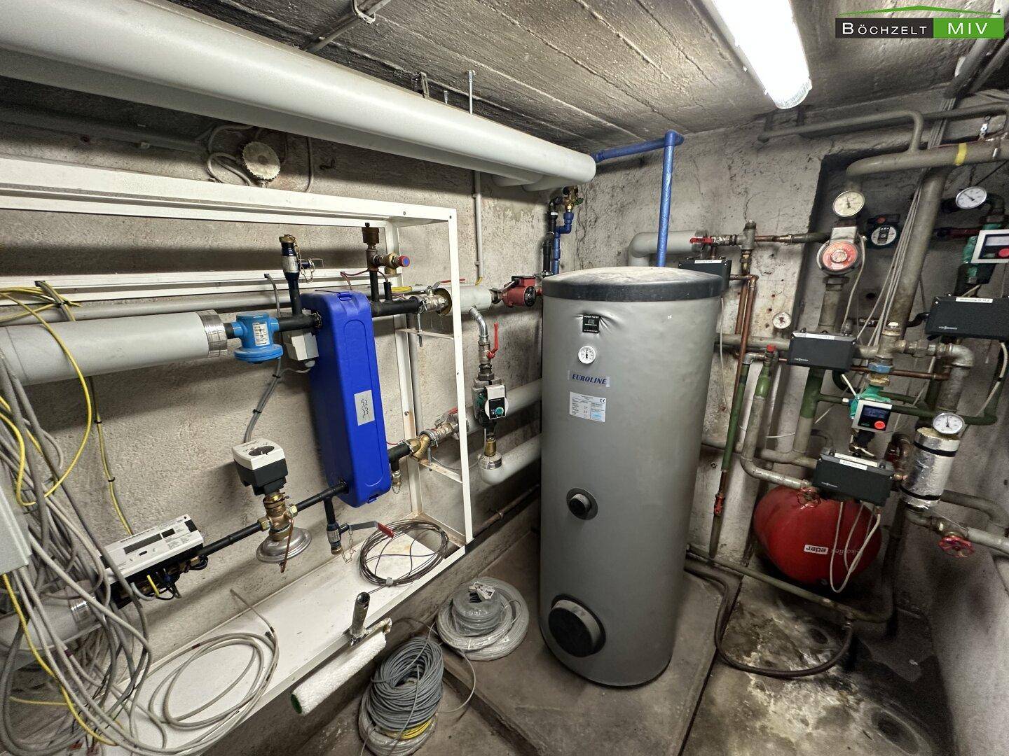 Heizungsraum mit Warmwasserspeicher und komplexer Verrohrung für die Gebäudetechnik.