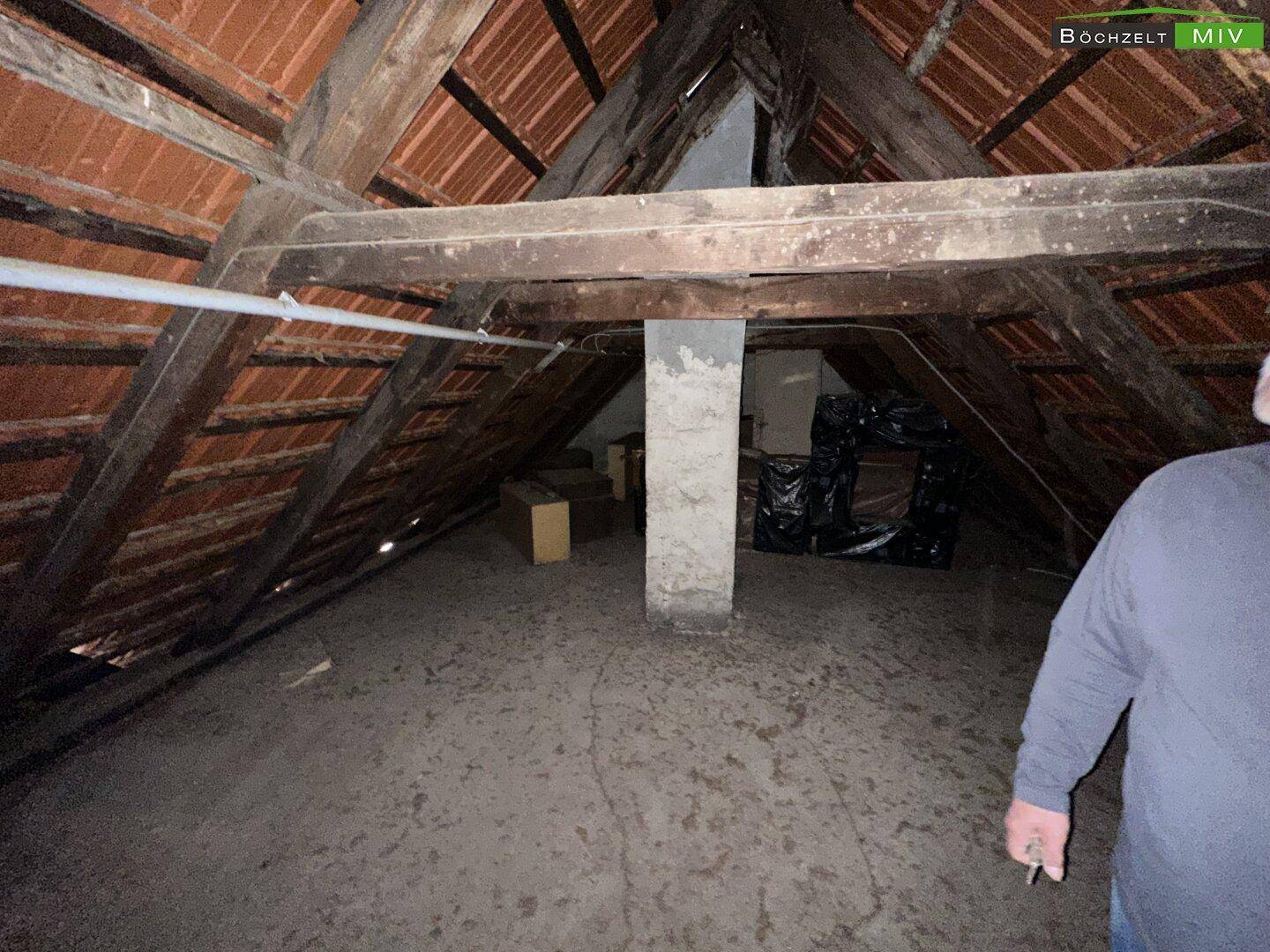 Geräumiger Dachboden mit sichtbaren Holzbalken und Ziegeln, bietet viel Stauraum.