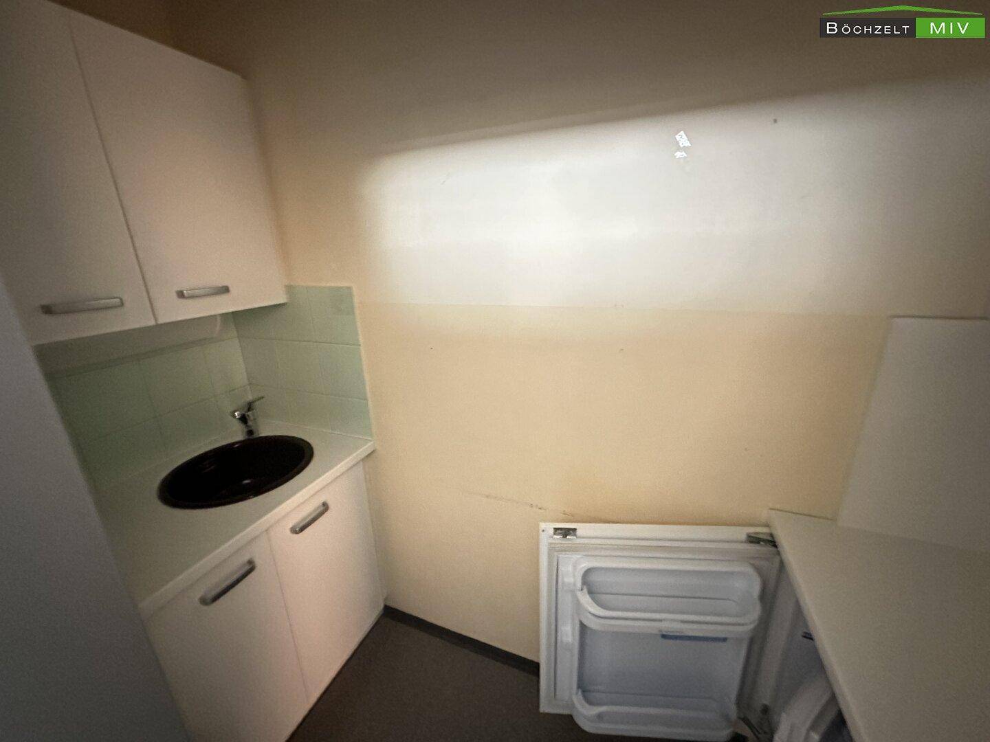Kleiner Wirtschaftsraum mit Waschbecken, Unterschränken und Platz für Geräte, ausgestattet mit Vinylboden.