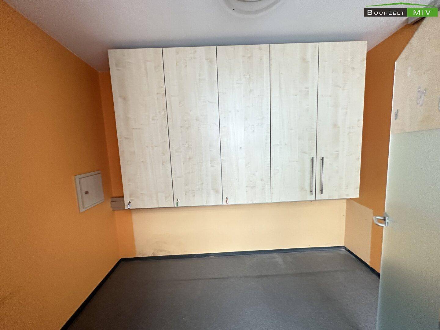 Kleiner Abstellraum mit hellen Hängeschränken und orangefarbenen Wänden, ausgestattet mit Vinylboden.
