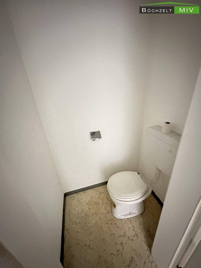 Einfache Toilette in einem kleinen Raum mit weißer Keramik und funktionaler Ausstattung.