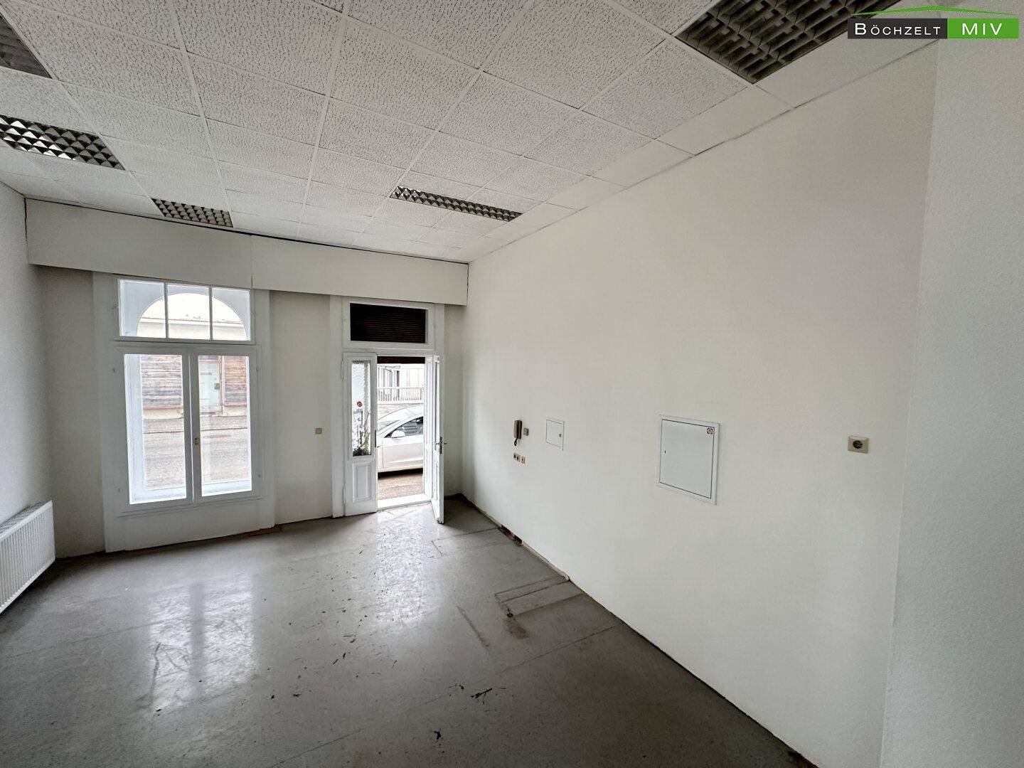 Heller Gewerberaum mit großen Fenstern zur Straße und Eingangstür, bereit für die individuelle Gestaltung.