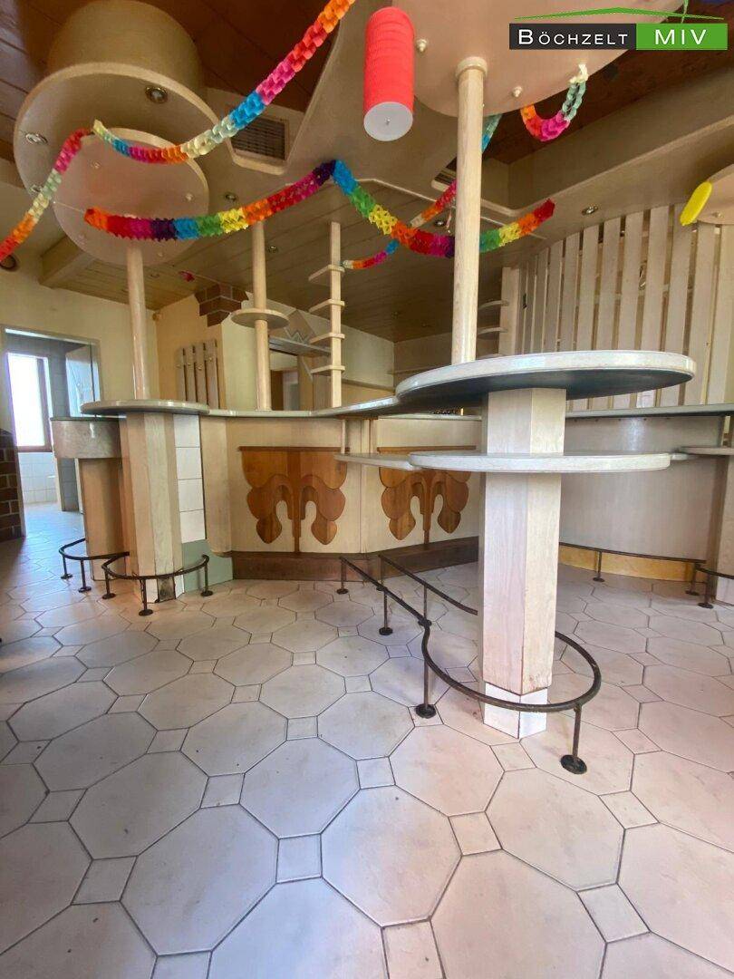 Innenansicht einer Bar oder eines Cafés mit einzigartigem Design, Fliesenboden und bunten Girlanden.