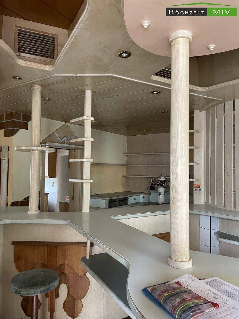 Nahaufnahme der Theke und der Regale einer Bar mit Holzelementen und Deckenventilation.