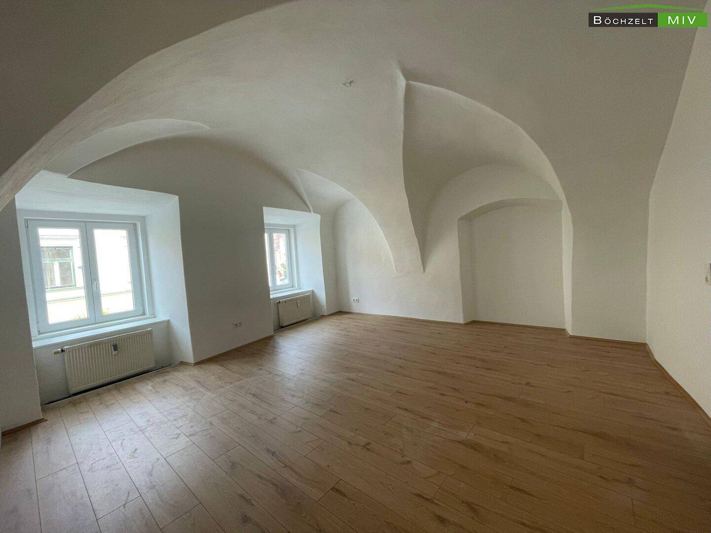 Geräumiger Raum mit gewölbter Decke und Holzboden, ideal für einen Wohn- oder Schlafbereich.