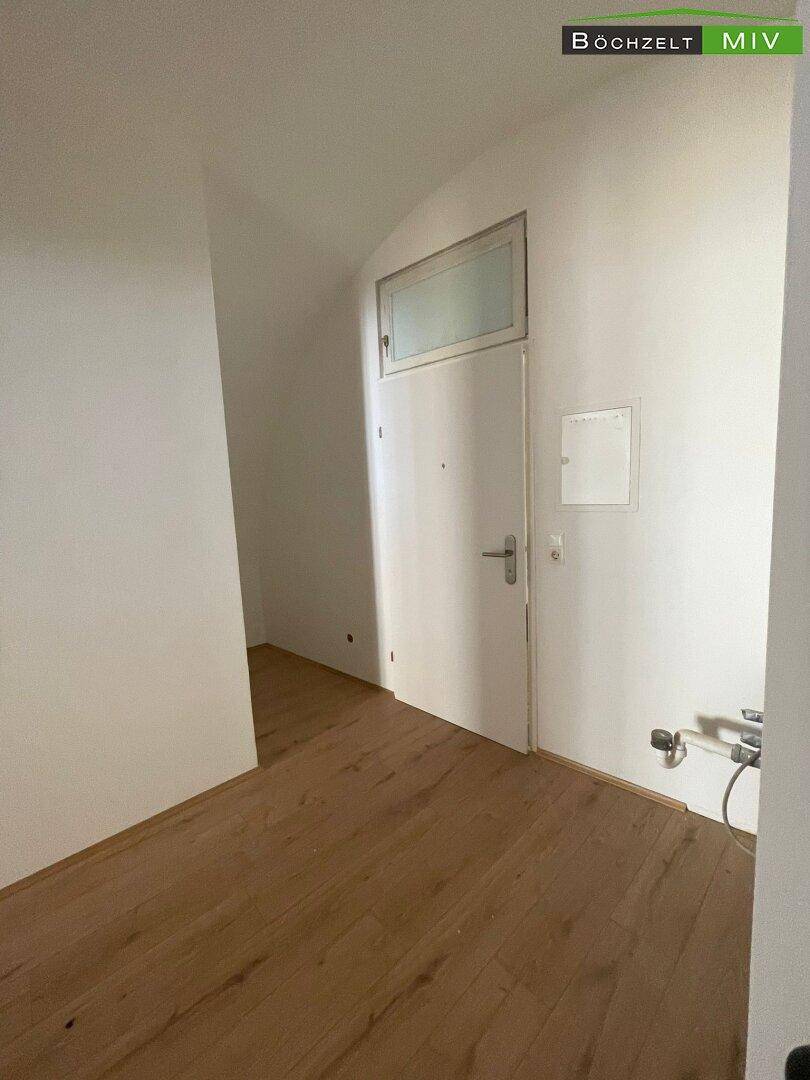 Eingangsbereich mit Holzboden und weißer Tür, die zu weiteren Räumen in der Wohnung führt.