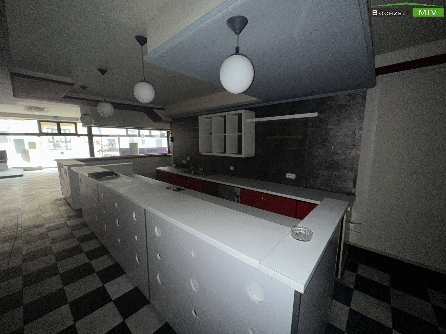 Detailansicht der Bar mit Theke, Regalen und Blick auf den Hauptraum des Nachtclubs.