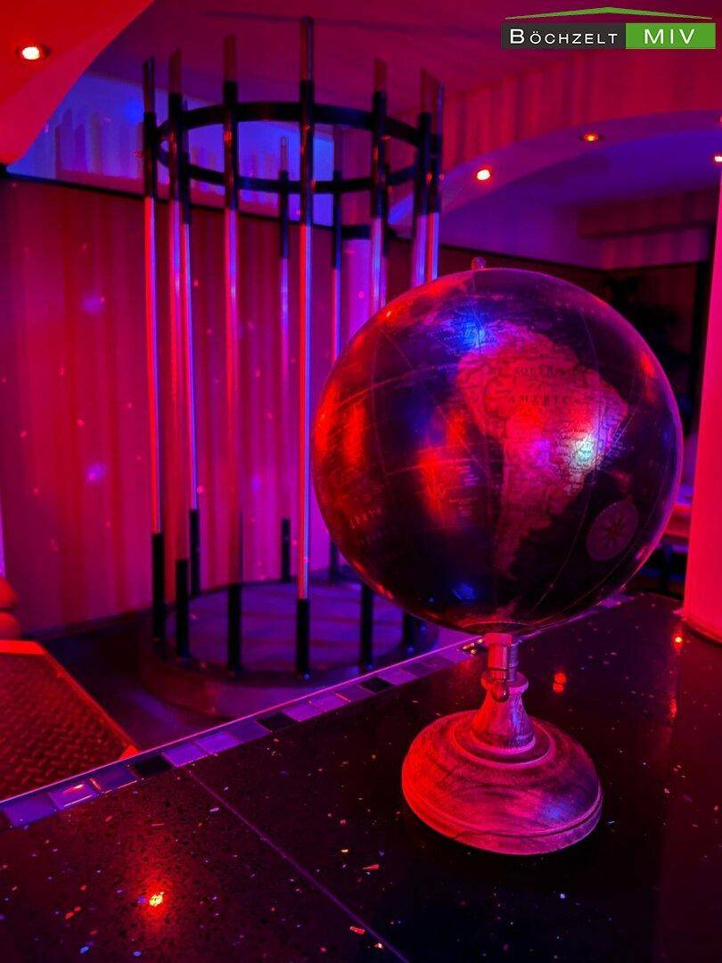 Dekorative Weltkugel auf einer glitzernden Oberfläche im Nachtclub mit farbiger Beleuchtung.