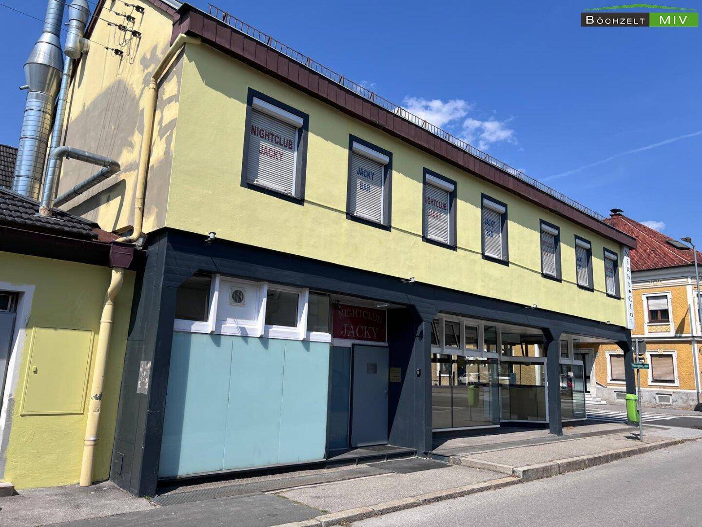 Außenansicht eines Gebäudes mit gelber Fassade und dunklen Akzenten, das als Nachtclub und Bar dient.