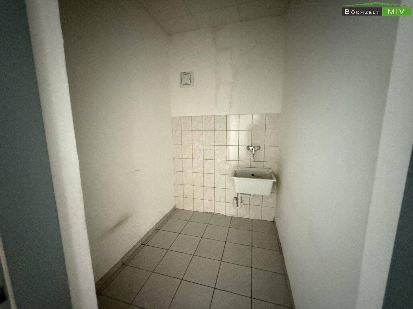 Kleiner Raum mit Fliesenboden und einem Waschbecken, geeignet als Abstell- oder Putzraum.