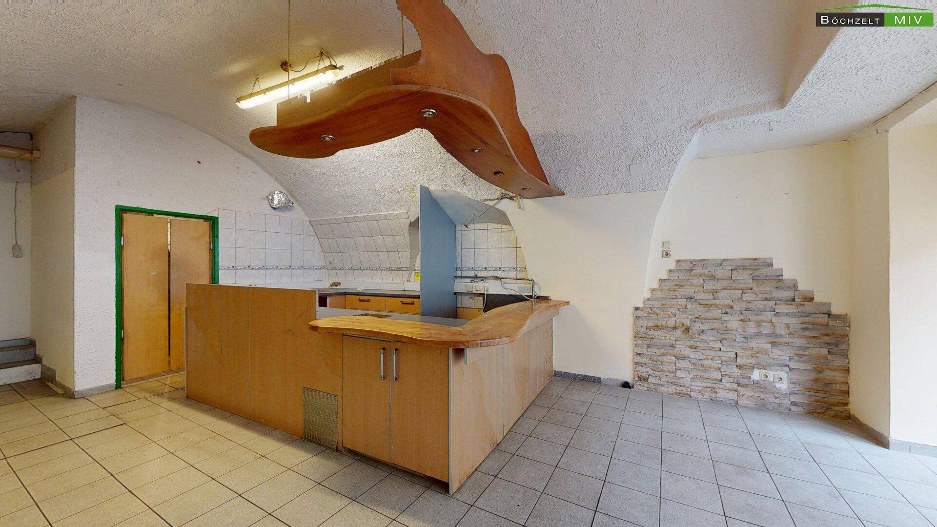 Gewerbefläche mit Thekenbereich, gefliestem Boden und einer markanten Steinwandverkleidung.