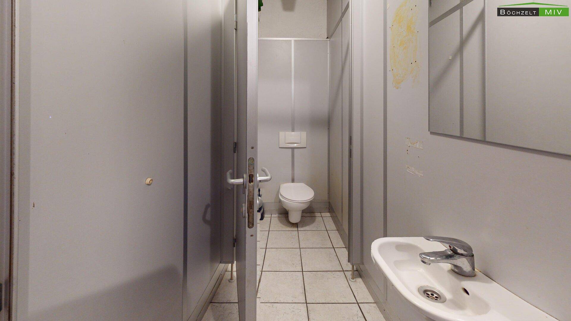 Toilettenraum mit WC, Waschbecken und gefliestem Boden, in sauberem und funktionalem Zustand.