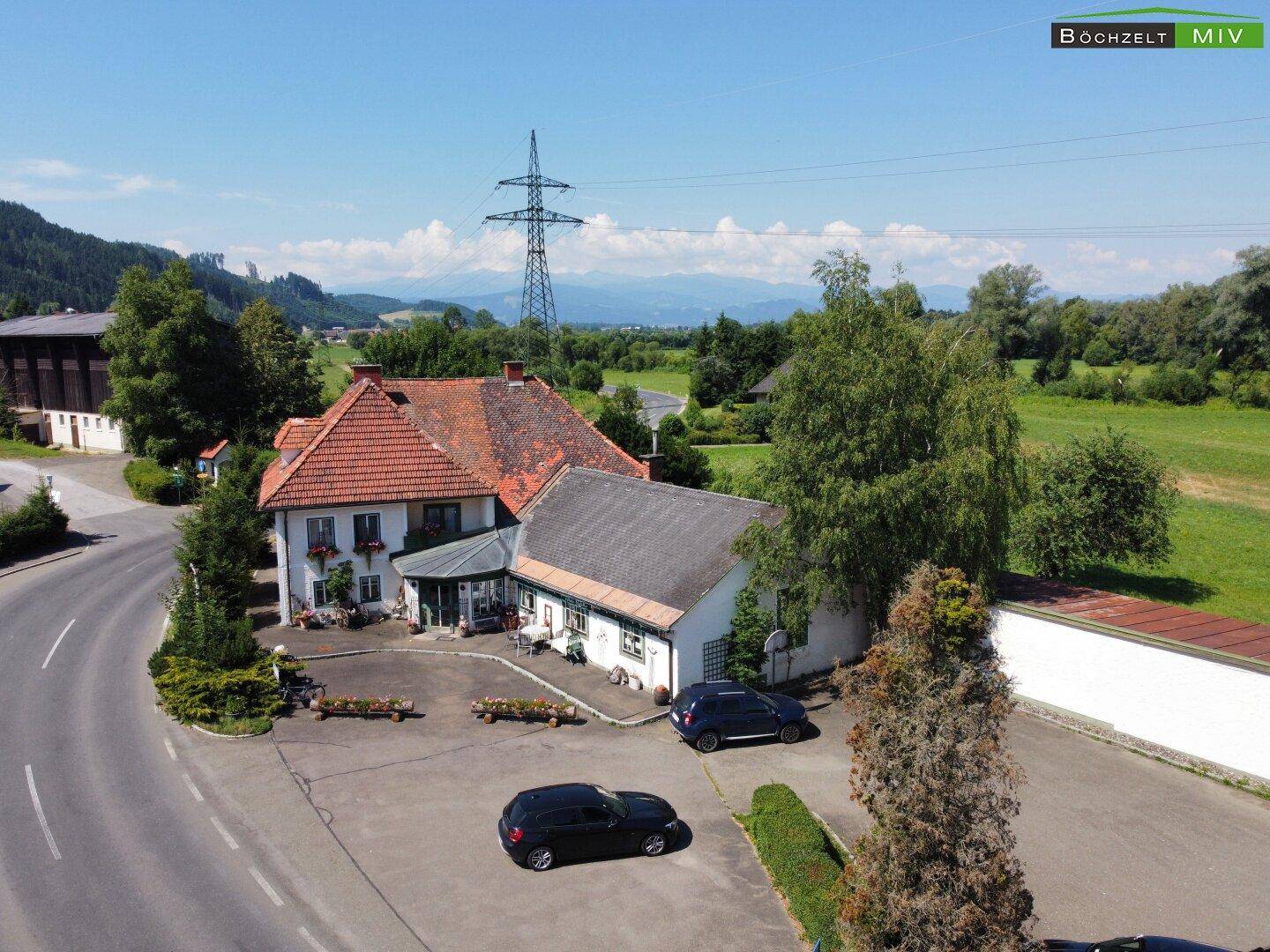 Luftaufnahme des Anwesens mit traditionellem Charme, umgeben von Bäumen und einer Zufahrtsstraße.