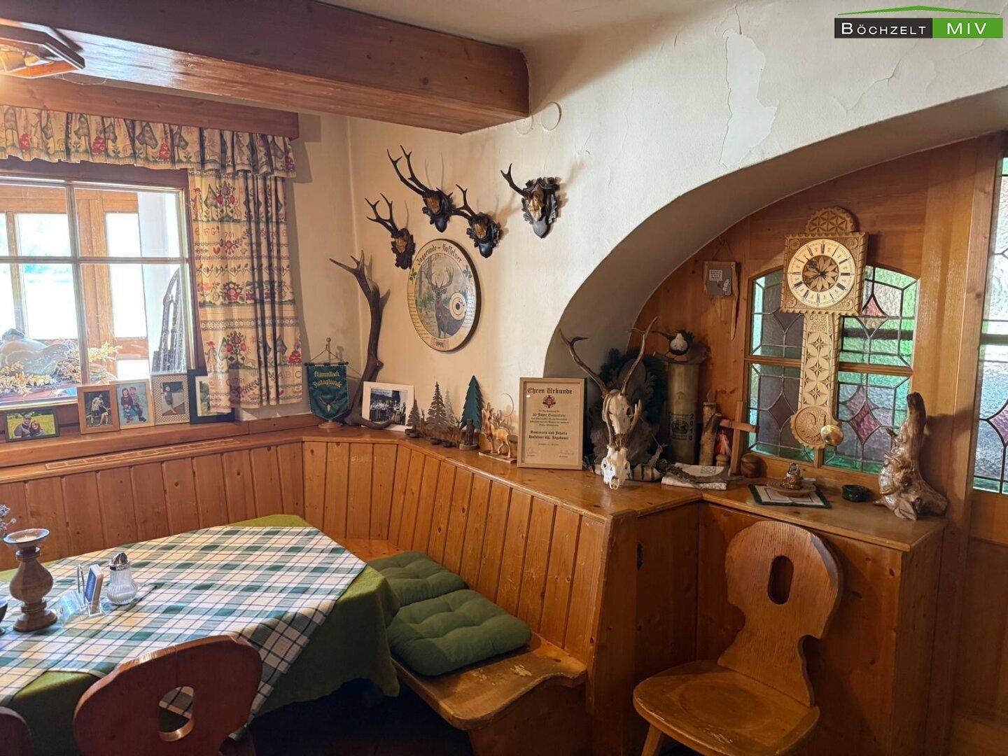 Gemütlicher Essbereich im traditionellen Stil mit Eckbank, Holzvertäfelung und Jagdtrophäen.
