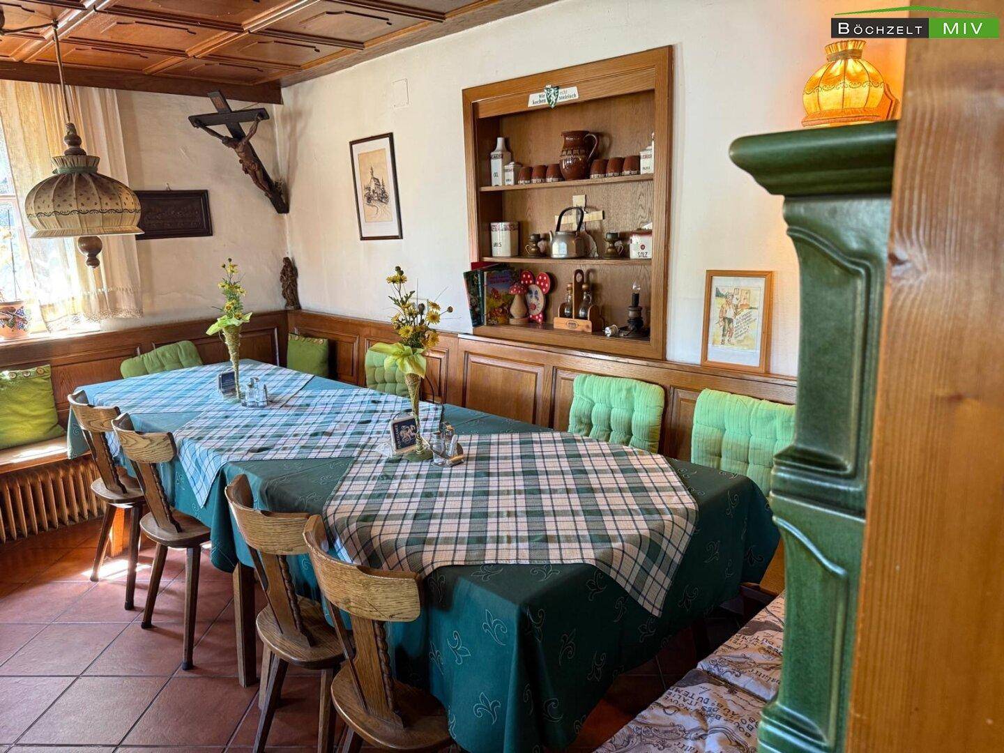 Geräumiger Speisesaal mit mehreren Tischen, Holzvertäfelung und einem traditionellen Kachelofen.