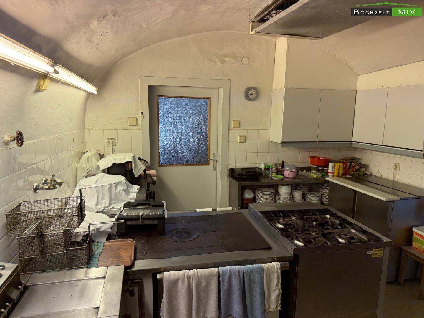 Gewerbliche Küche mit umfangreicher Ausstattung, Gasherd, Fritteusen und gefliesten Arbeitsbereichen.