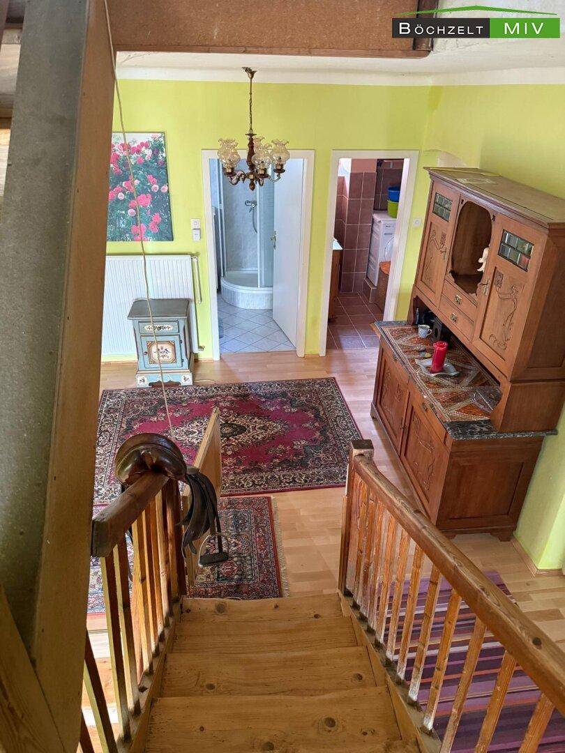Treppenhaus mit Holzstufen und Teppichläufern, das zu weiteren Räumen führt.
