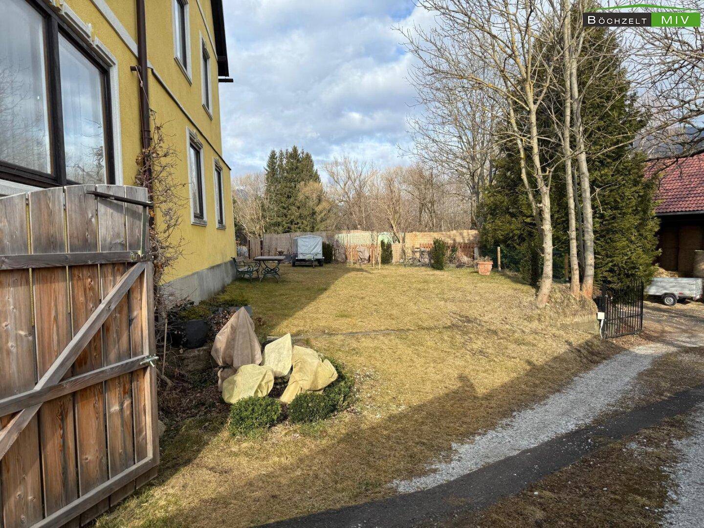 Großer Gartenbereich mit Rasenfläche, Bäumen und einem Kiesweg.