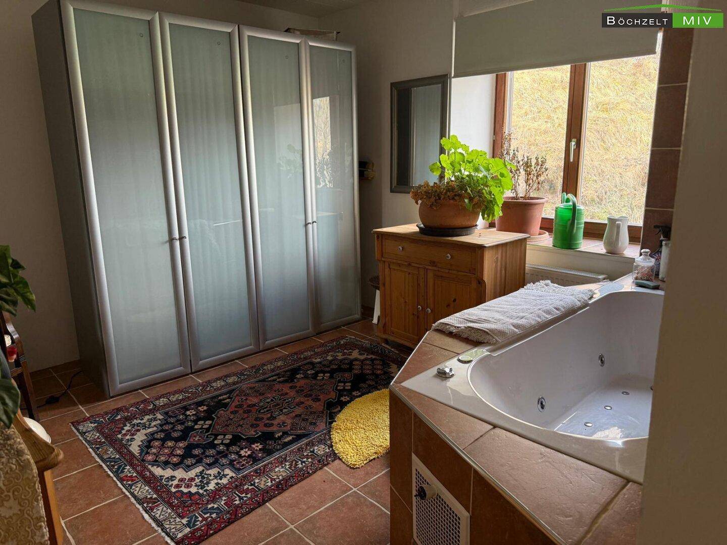Geräumiges Schlafzimmer mit Kleiderschrank, Teppich und einer integrierten Badewanne.