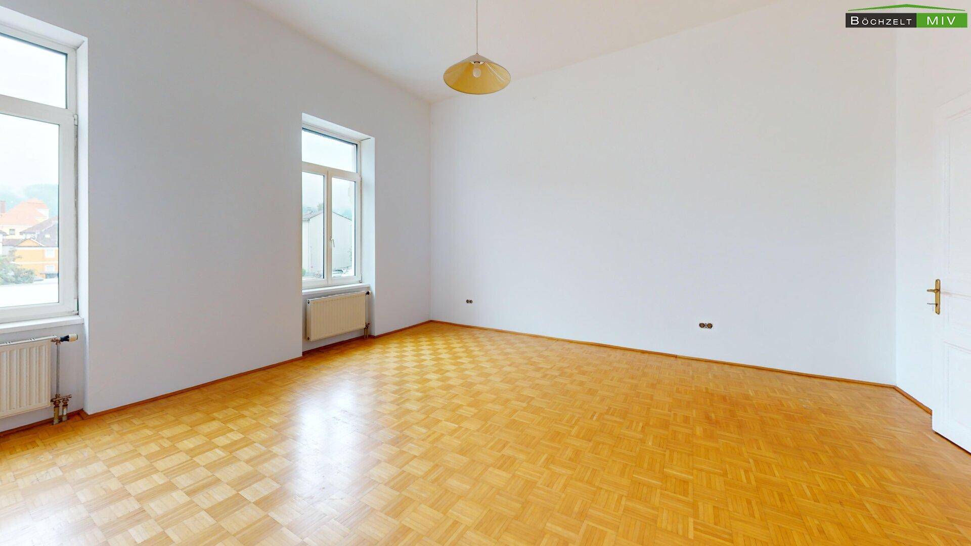Geräumiges Zimmer mit zwei Fenstern und Parkettboden, ideal für individuelle Gestaltungsmöglichkeiten.