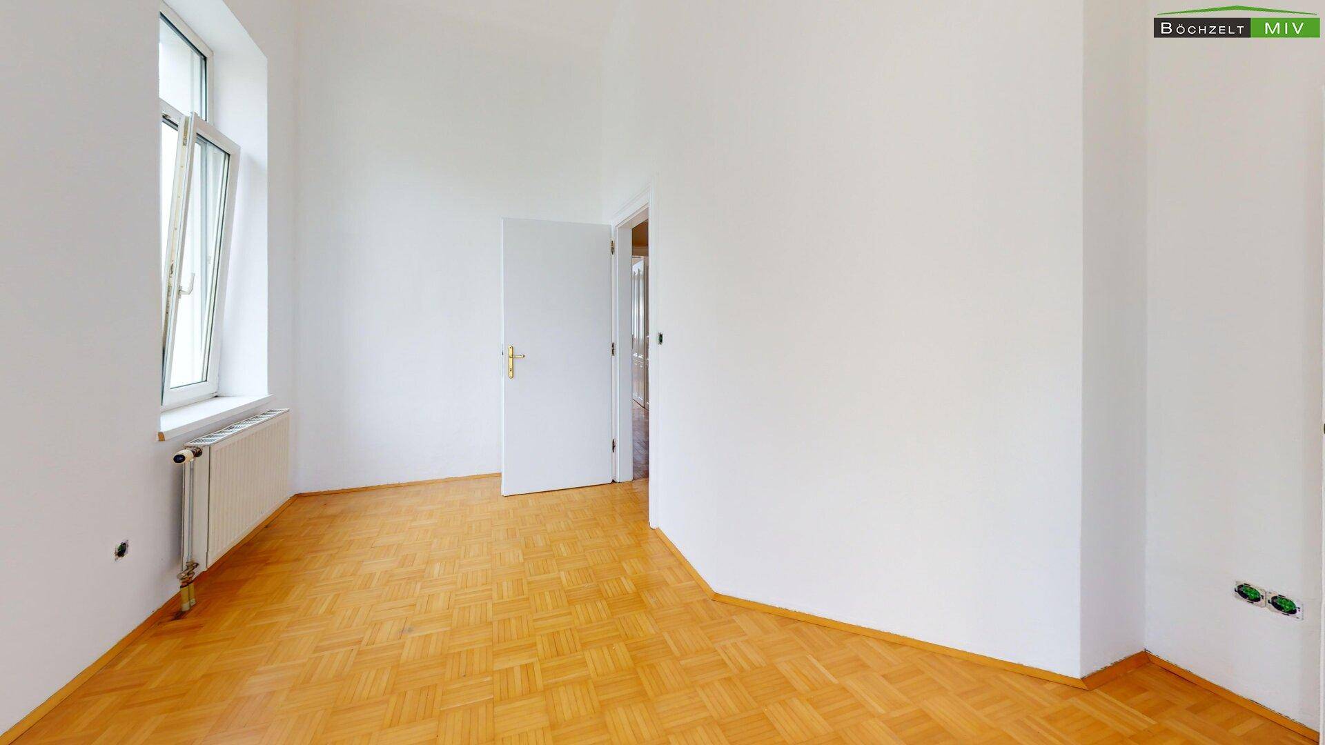 Heller Raum mit Parkettboden und Fenster, bietet eine gute Basis für ein gemütliches Zuhause.