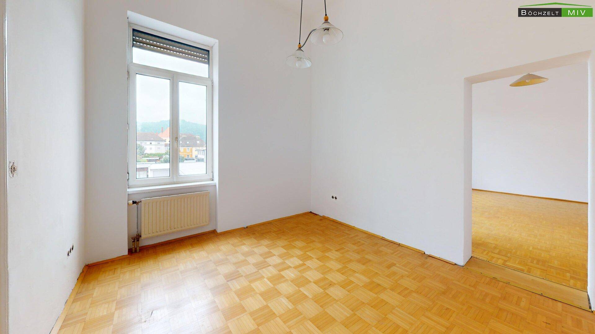 Helles Zimmer mit Parkettboden und Fenster, bietet einen weiten Blick in die Umgebung.