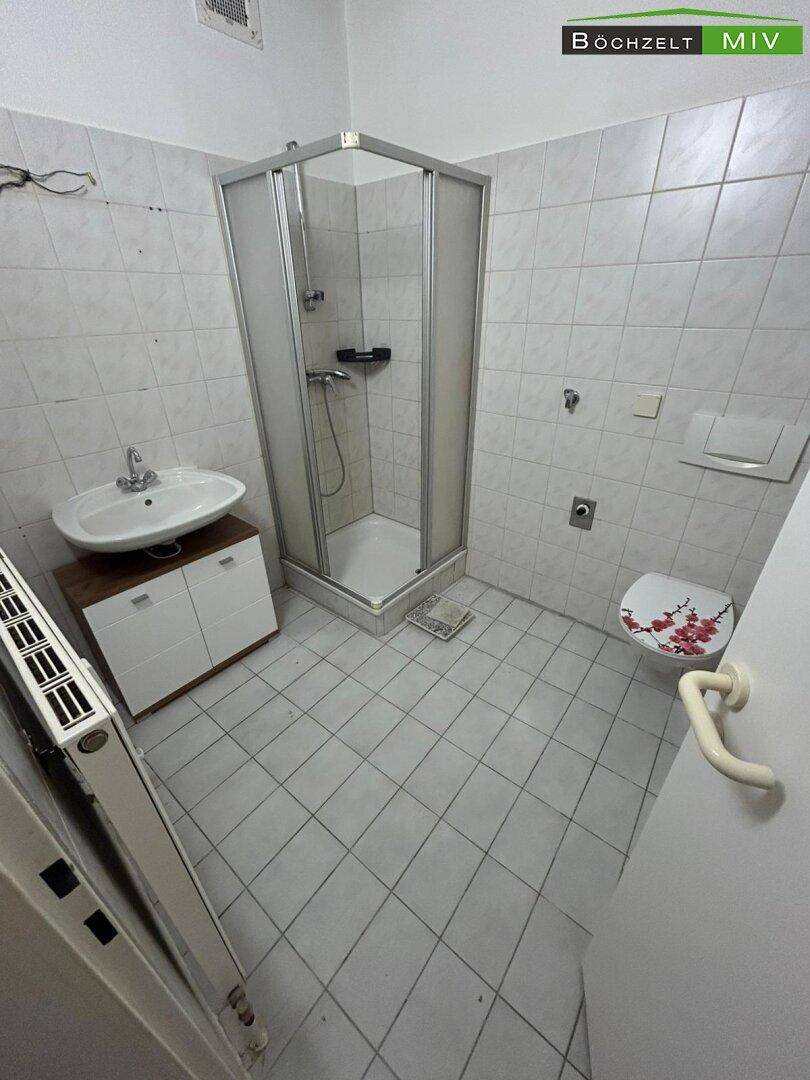 Funktionales Badezimmer mit Duschkabine, Waschbecken und WC, hell gefliest.