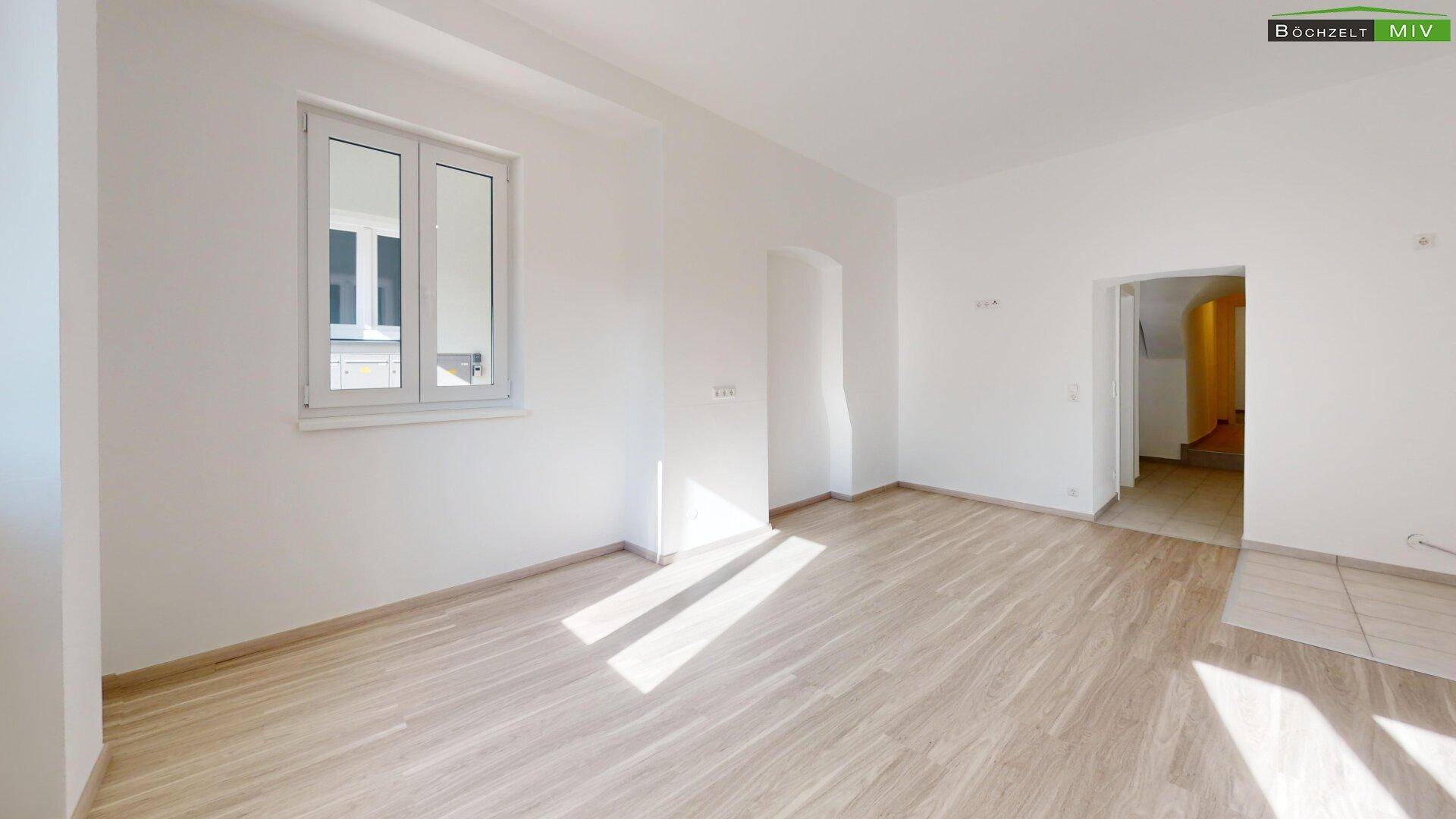 Geräumiges, helles Zimmer mit Laminatboden und weiß gestrichenen Wänden, durchflutet von natürlichem Licht.