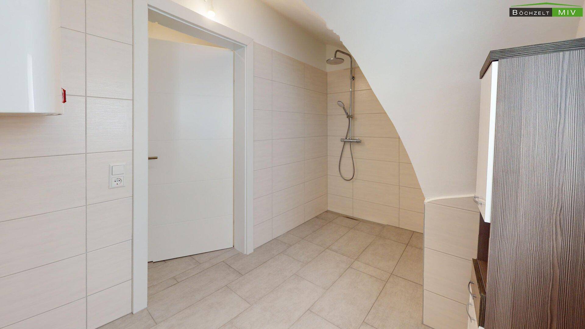 Modern gefliestes Badezimmer mit Duschbereich, Dachschräge und einem Waschbeckenunterschrank.