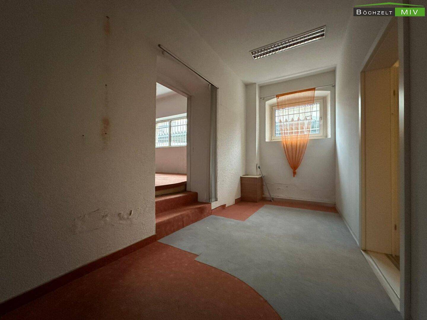 Übergangsbereich in einem Gewerbeobjekt mit Teppichboden, einem Fenster und einfacher Beleuchtung.