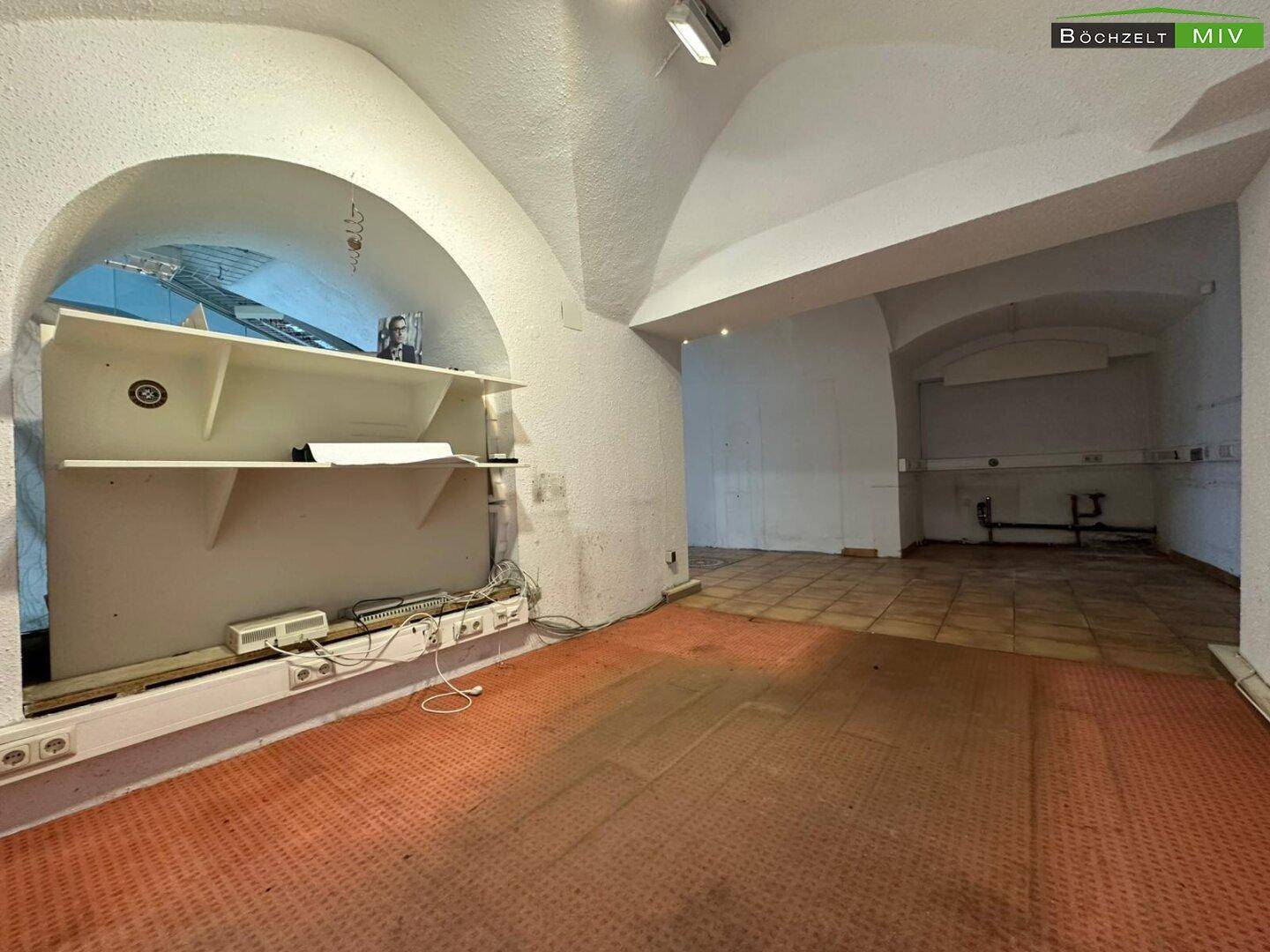 Nischenbereich in einem Gewerberaum mit Regalen, Verkabelung und Fliesenboden.