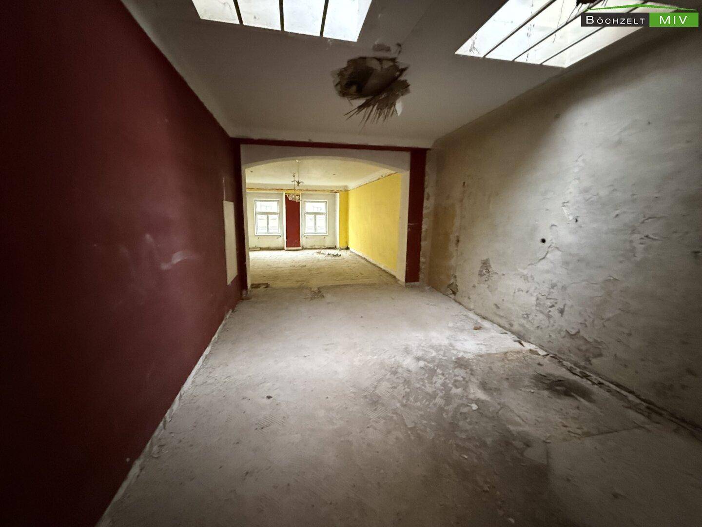 Lange Raumflucht mit unterschiedlichen Wandfarben und unfertigen Böden, die auf Renovierung wartet.