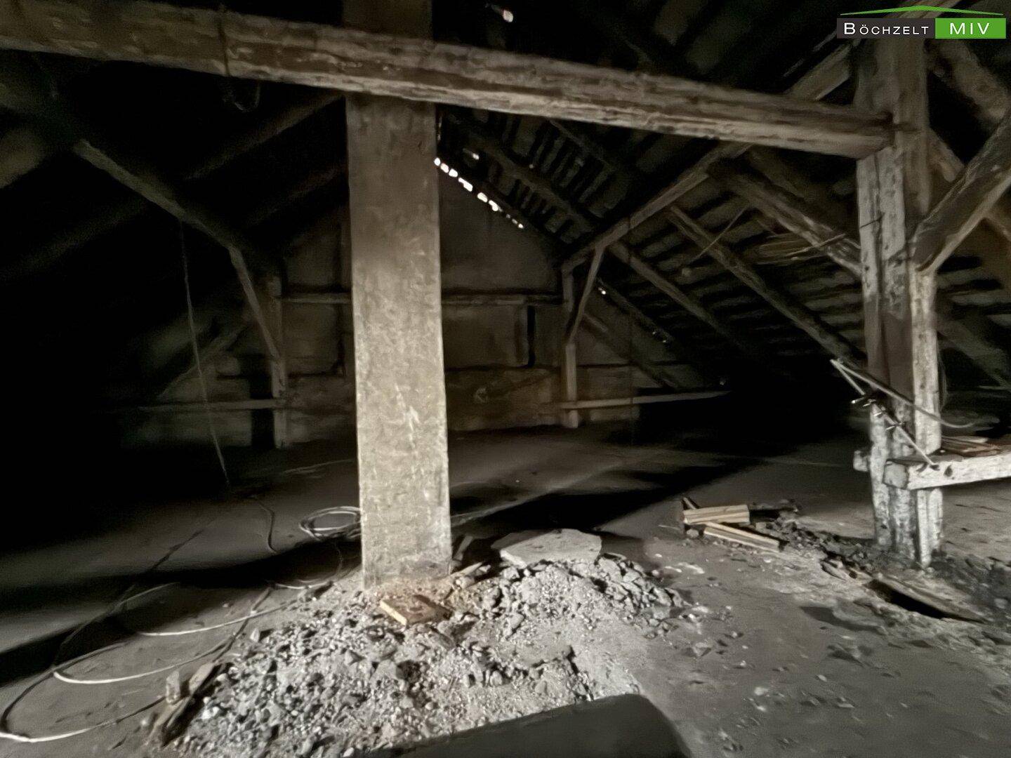 Großer Dachboden mit freiliegenden Holzbalken und einem Betonpfeiler, der auf Renovierung wartet.