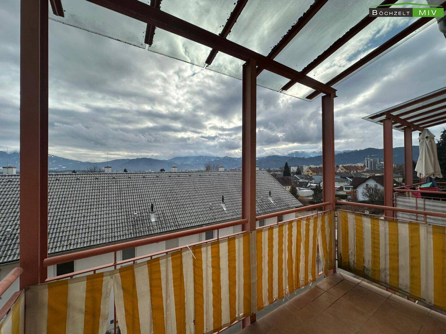 Geräumiger Balkon mit Überdachung und Panoramablick auf die umliegende Landschaft und Berge.