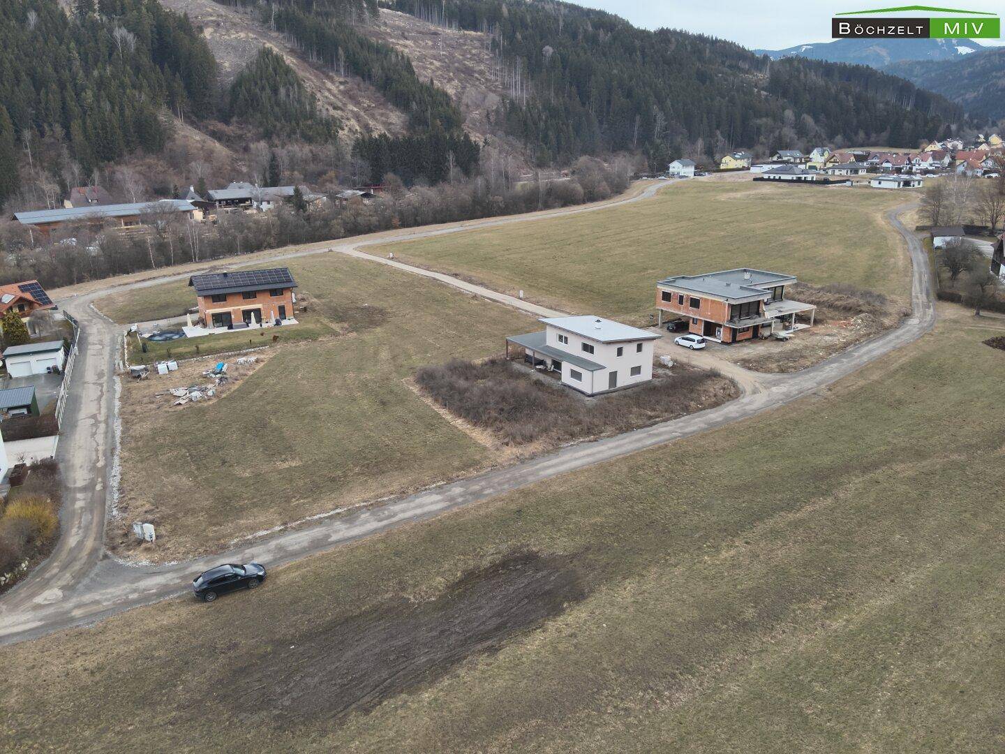 Luftaufnahme eines Wohngebiets mit modernen Häusern und unbebauten Grundstücken in einer ländlichen Umgebung.