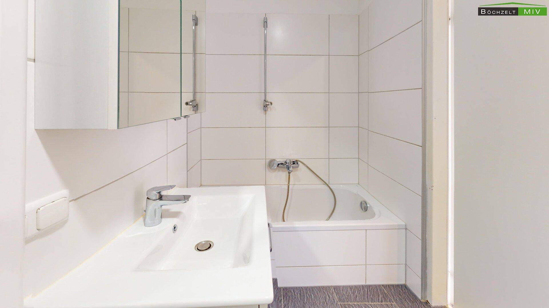 Funktionales Badezimmer mit Badewanne, Waschbecken und Spiegelschrank.