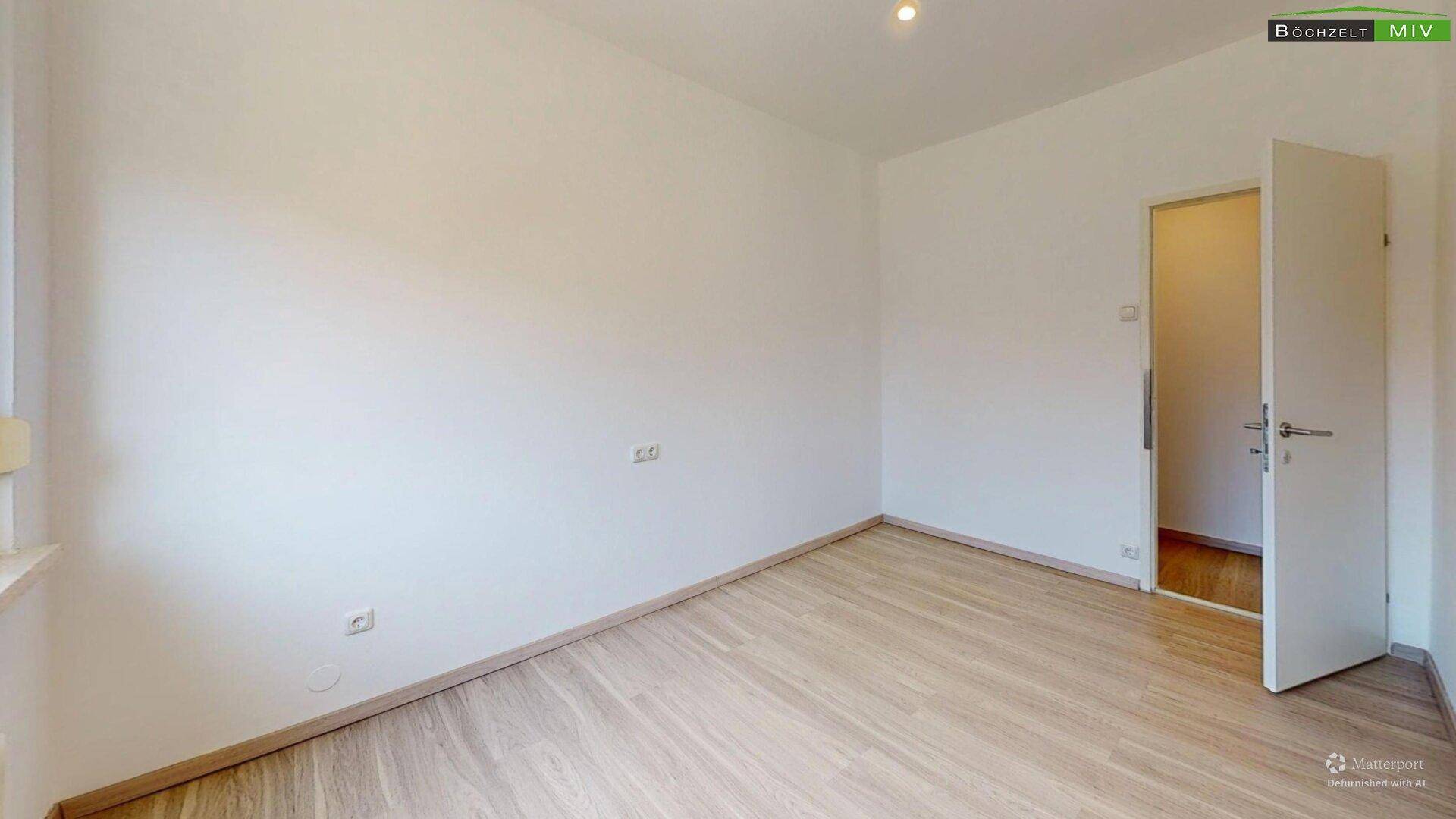 Einfaches, helles Zimmer mit Laminatboden und weiß gestrichenen Wänden.