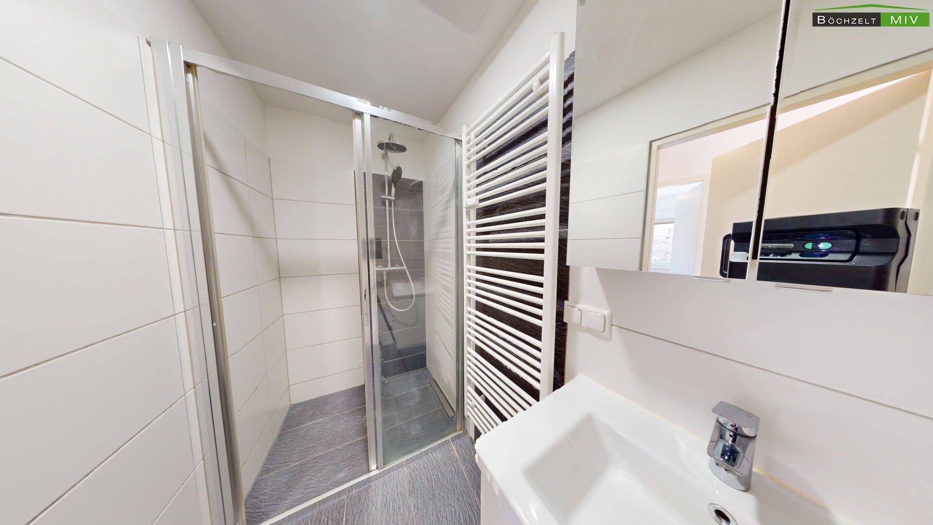 Modernes Badezimmer mit Duschkabine, Waschbecken und beheiztem Handtuchhalter.