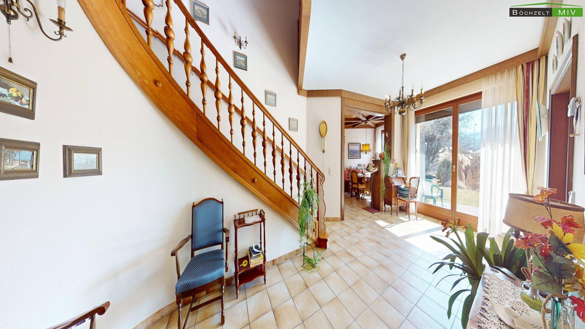 Geräumiger Flur mit Holztreppe, Terrakotta-Fliesen und Zugang zu weiteren Wohnbereichen.