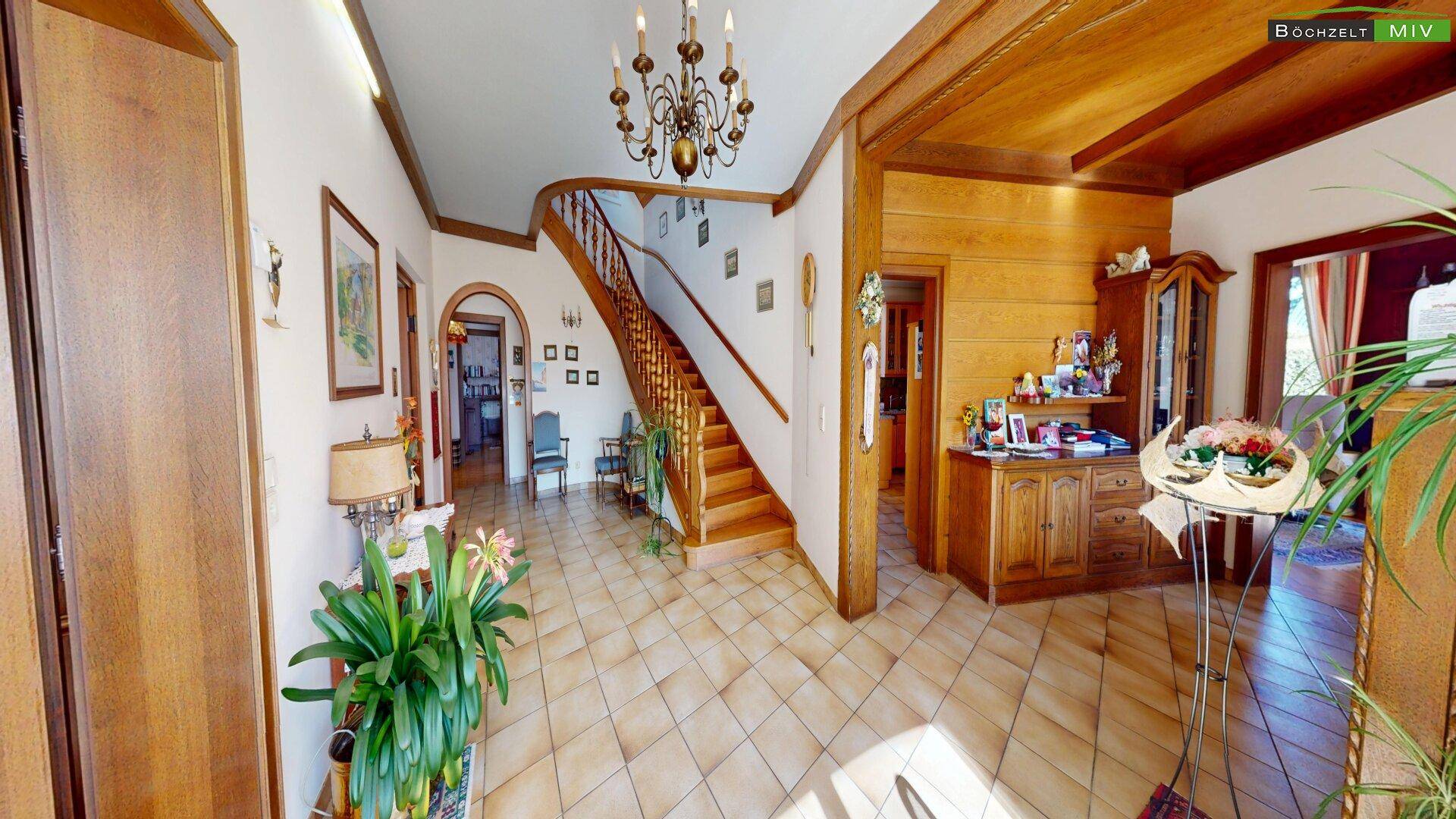 Heller Eingangsbereich mit eleganter Holztreppe, Terrakotta-Fliesen und traditionellen Möbeln.