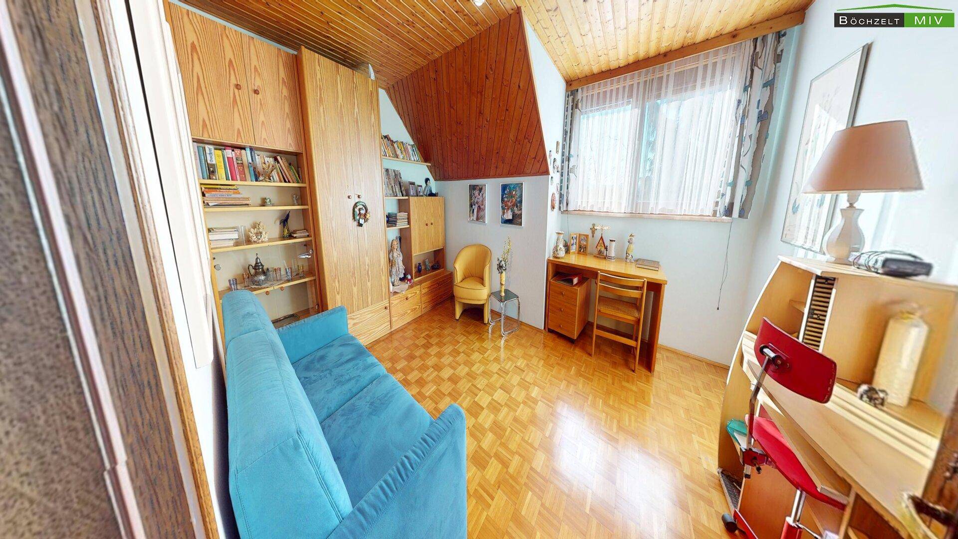 Helles Arbeitszimmer mit Holzdecke, Parkettboden und großem Fenster.
