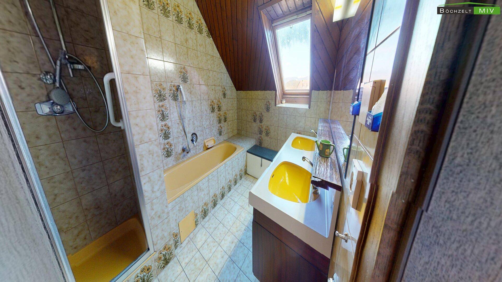 Badezimmer im Dachgeschoss mit Badewanne, Dusche und gelben Sanitärobjekten.