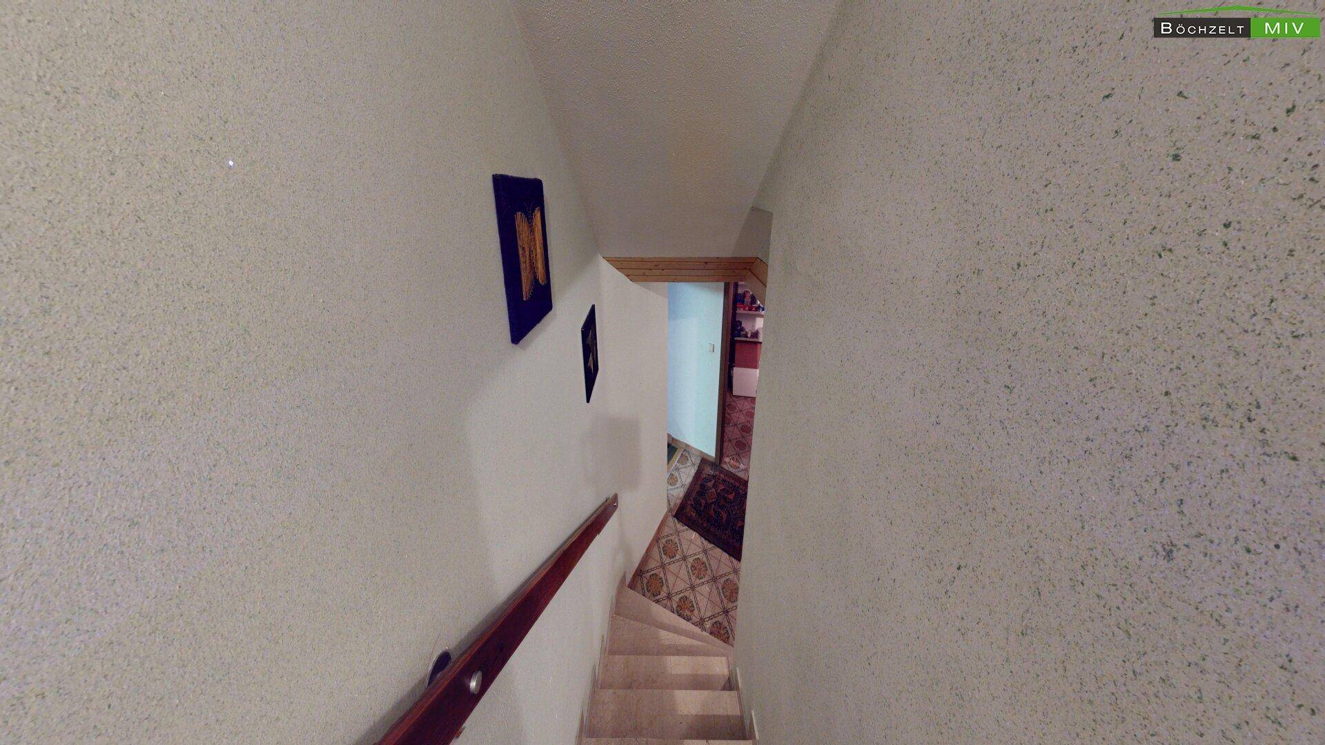 Treppenhaus mit hellem Fliesenboden und weiß gestrichenen Wänden.