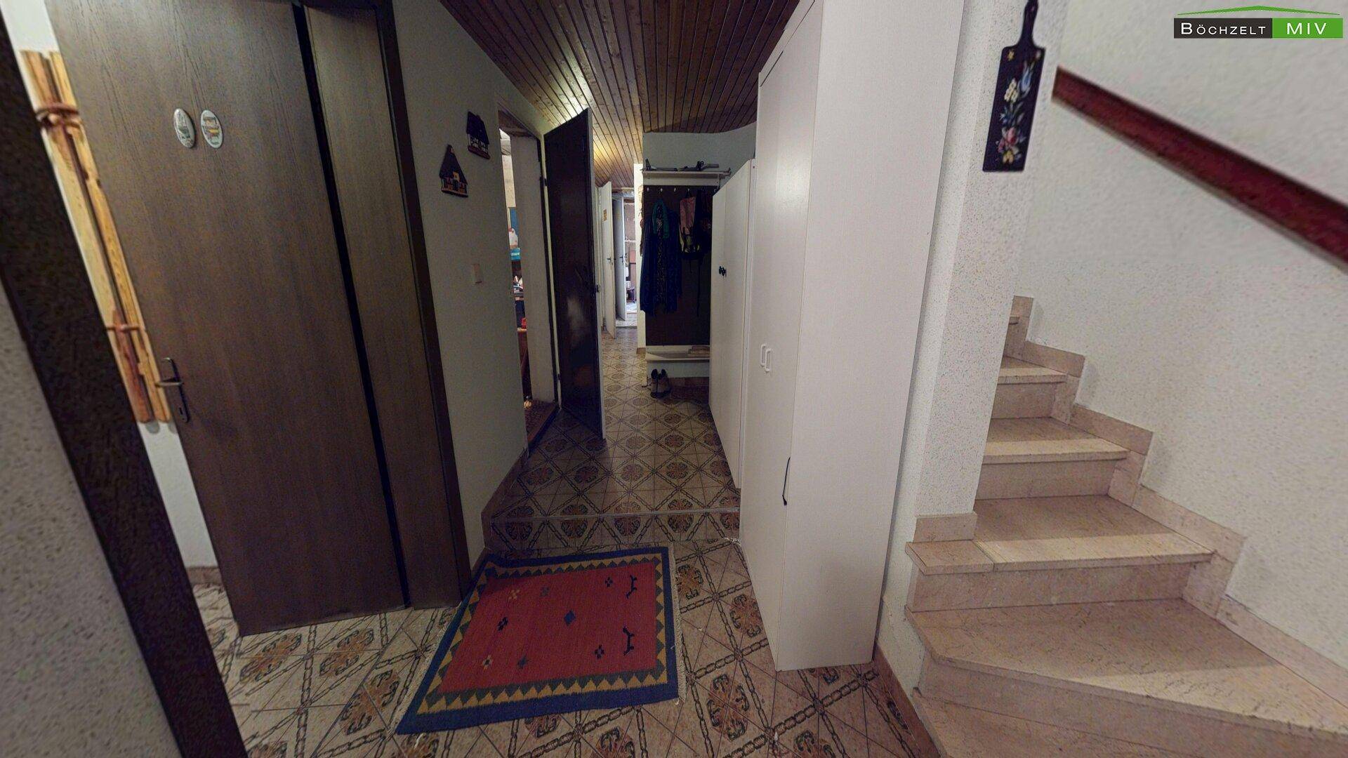 Eingangsbereich mit Fliesenboden, Garderobe und Treppenaufgang.