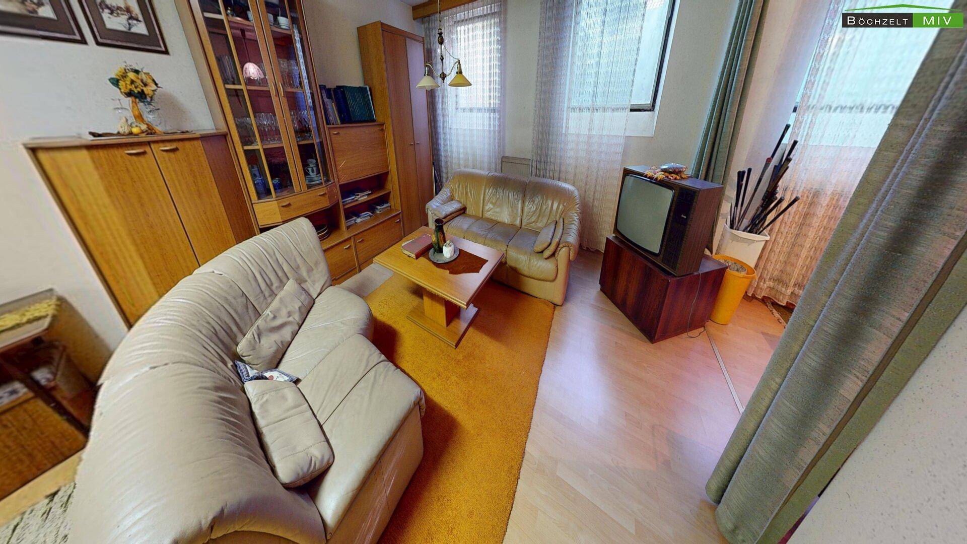 Gemütliches Wohnzimmer mit beigen Sofas, Holztisch und einem Teppich in warmem Orangeton.
