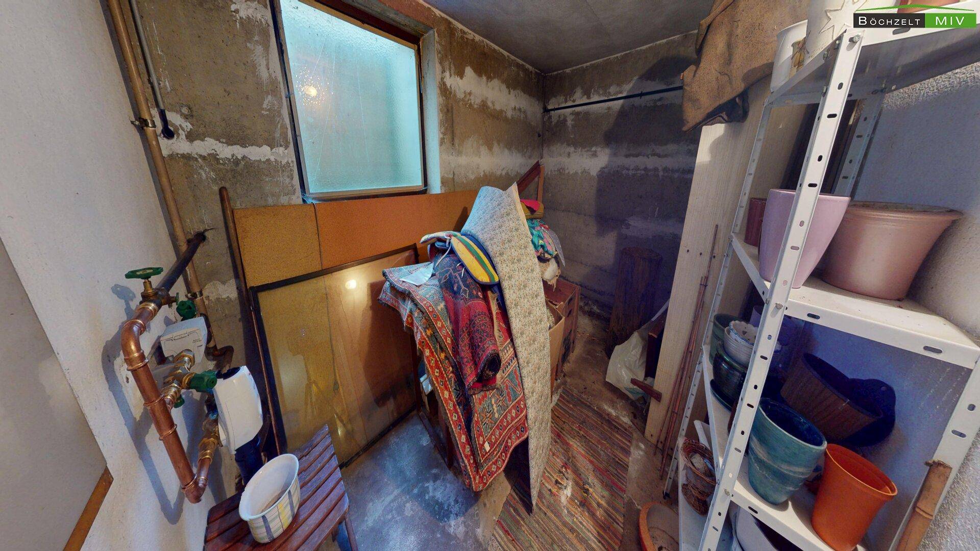 Weiterer Kellerraum mit Betonwänden und einem kleinen Fenster, genutzt als Abstellfläche.