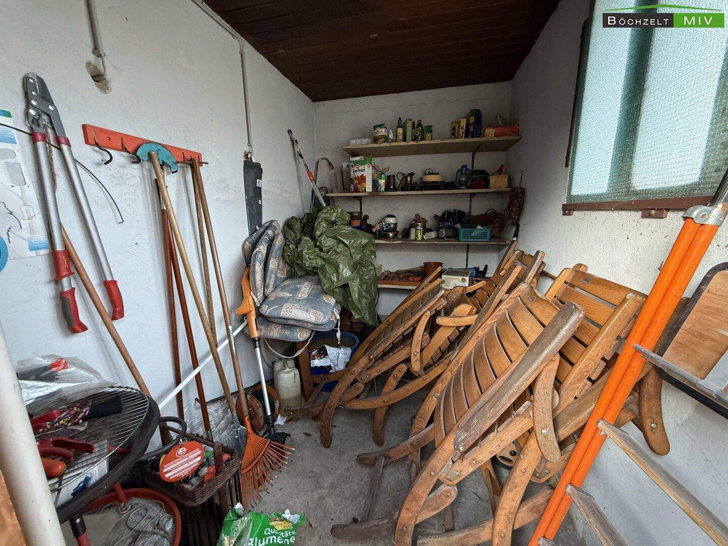 Geräteschuppen mit Gartenwerkzeugen und zusammengeklappten Gartenmöbeln, bereit für den Einsatz.